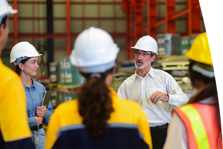 Construction team meeting in industrial warehouse with safety helmets